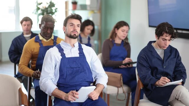 Workers of different ages listen attentively to the teacher and take notes in notebooks during a lecture at the learning center. High quality 4k footage
