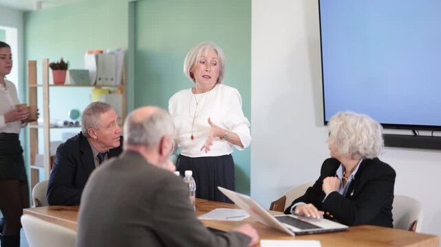 Senior business community listening to female speaker or presenter during round table conference. Business session, consultative meeting, coaching course, personal growth courses, cooperation plans