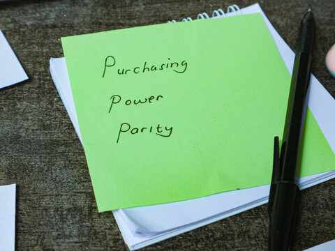 Green Sticky Note with Handwritten Words Purchasing Power Parity on Wooden Desk