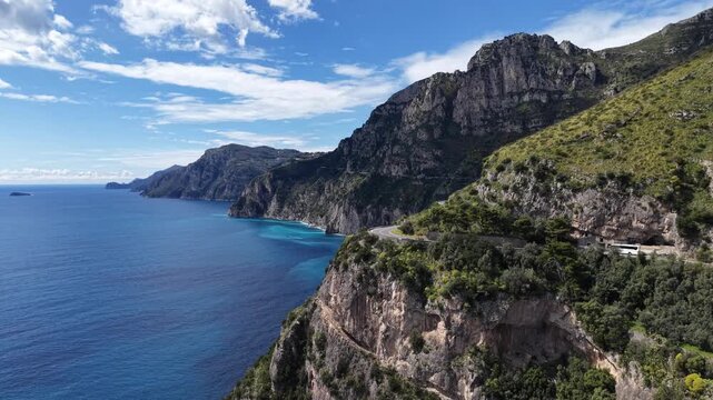 Aerial view of the dramatic cliffs of Via Nastro Azzurro meeting the deep blue sea, creating a striking contrast of rugged terrain and serene waters, Vico Equense, Campania, Italy.