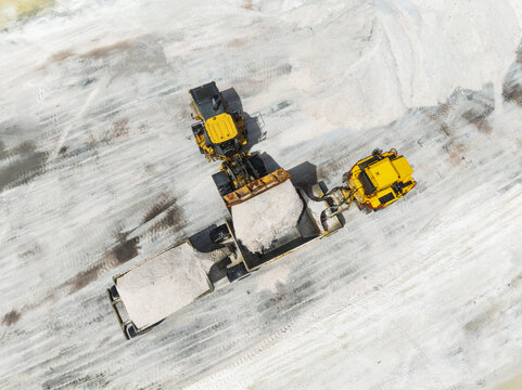 Aerial view of heavy machinery processing salt piles, the stark white contrasting against the machinery's yellow, Walvis Bay, Erongo Region, Namibia.