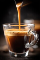 Fototapeta premium Freshly brewed espresso pouring into a clear glass cup with rich crema on top