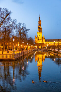 Travel, tourism: Plaza de Espa&ntilde;a illuminated at dusk, reflecting in the water, with ducks swimming, in Seville, Spain.