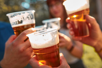 People holding beer cups and enjoying summertime outdoors.