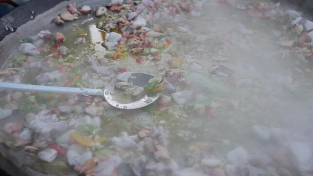 Sizzling seafood paella with shrimp and mussels cooking in a giant traditional pan. Authentic Spanish street food steaming at an outdoor festival, a delicious culinary experience.