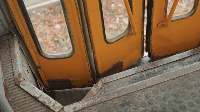 Closeup vintage bus doorway showing worn metal steps and rusted threshold, textured yellow doors, diamondplate floor, gritty urban atmosphere, cinematic creator perspective by street photographer