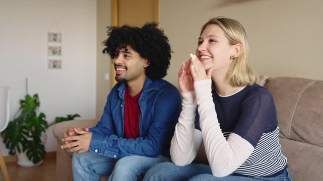 Diverse couple watching sports and reacting emotionally