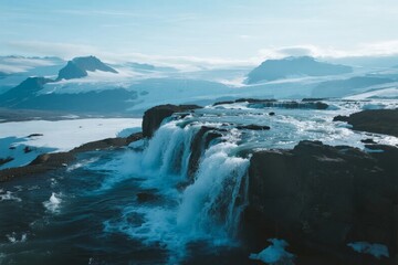 Fototapeta premium Glacial waterfall cascading over rocky terrain in a snowy mountain landscape