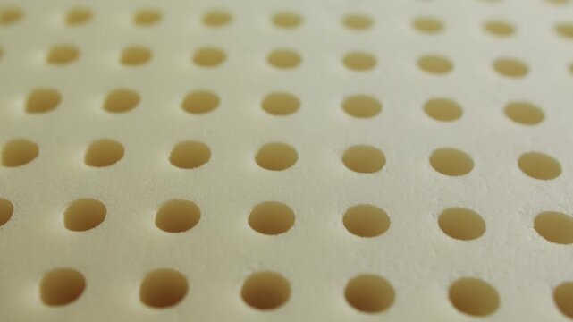 Close-up of a memory foam pillow layer with perforated surface. Soft breathable material with pressure-relief and shape-retaining properties. High quality 4k footage