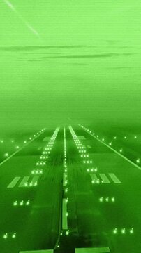 Vertical pov from cockpit of airplane landing on runway with green night vision effect in Milan, Italy