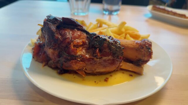 Pork knuckle served with crispy French fries on the table, tender, smoky, and packed with taste. High quality 4k footage
