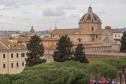 Elevated view from Capitoline Hill showing Rome architecture, Italian pine trees and the dome of Santa Maria in Aracoeli. Calm city scene in cloudy weather.
