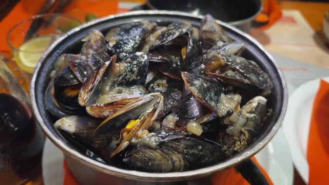 Pot of cooked mussels served with a spicy five-pepper sauce in a restaurant specializes in mussel dishes, tender, bold, and packed with flavor. High quality 4k footage