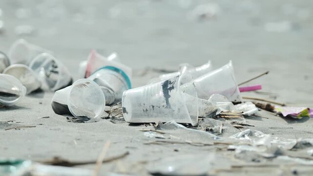Close up of scattered plastic trash on Lingayen beach sand under soft daylight