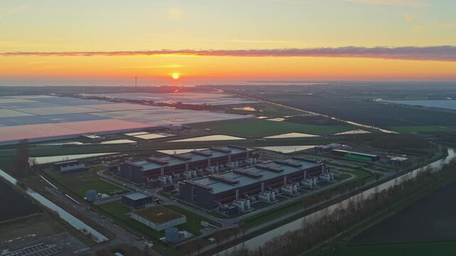 Aerial perspective of a large, modern data center facility in the dutch countryside during a vibrant sunrise, highlighting technology and innovation