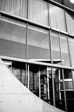 Monochrome exterior architecture facade of concrete and glass with modern curve entrance where strong lines form an abstract contemporary building statement