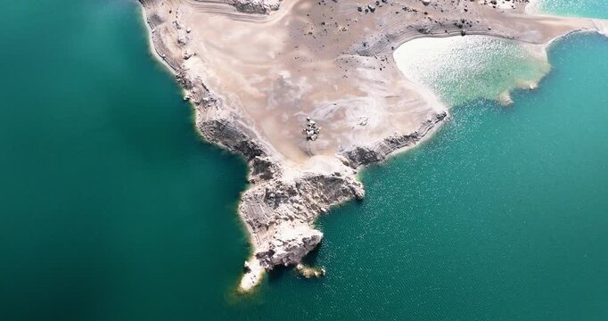 Aerial view of calcium carbonate lime deposits and exposed sediment shoreline with beautiful turquoise waters at Canales Reservoir Spain during drought. Spanish mountain nature reserve
