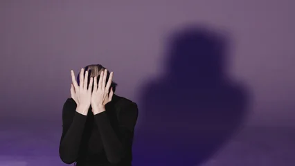 A close-up video of a young woman moving her hands away from her face to reveal a worried, searching gaze. Concept of psychological distress and human vulnerability. © Ulia Koltyrina