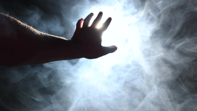 Man's hand reaching for powerful light beam