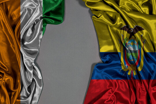 Silk Flags Of Ivory Coast And Ecuador Draped On Gray Background For International Concept