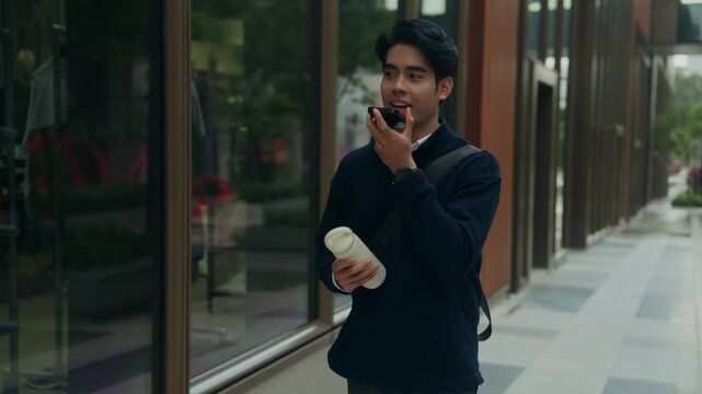 Young office worker steps out for a midday reset, talking on his smartphone during lunch, reflecting modern work life where flexible hours and soft hustle define the new concept of corporate life
