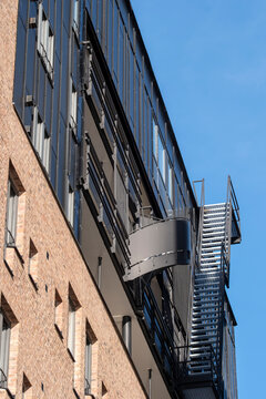 Urban building with vertical metal fire escape stairs and windows under open sky showing architecture safety access and modern structure design
