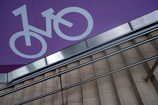 Urban stairs and steps with bicycle sign in purple showing transport access and railing near modern architecture for mobility direction concept