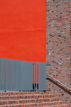 Minimal urban wall in red brick with fence beside stairs and steps showing strong texture contrast for abstract architecture background design