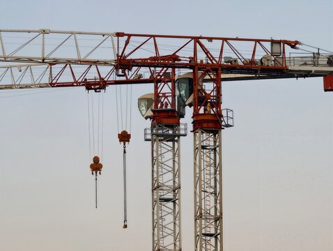 Massive cranes with steel arms reach high above construction zone as workers assemble structures