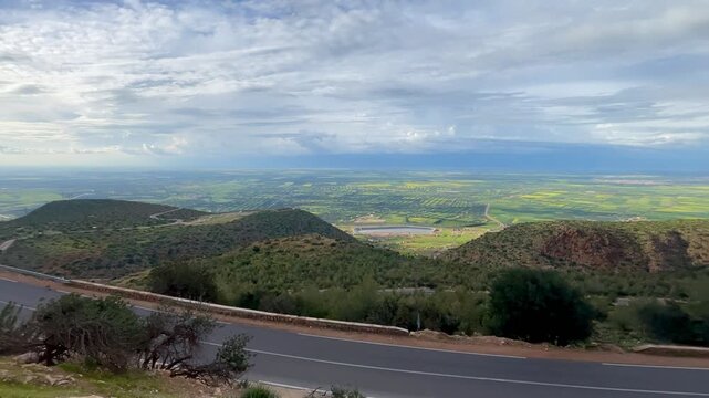 Beni Mellal, Morocco &ndash; March 26, 2026: I stood at a sharp hairpin bend in Afourer, capturing a wide-angle view of the winding road ahead. Below, the green plains of Beni Mellal stretched out, with rol