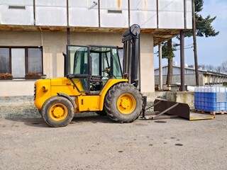 Yellow forklift stands idle outside factory. Loading bay forklift with crates in industrial yard © Vladimir