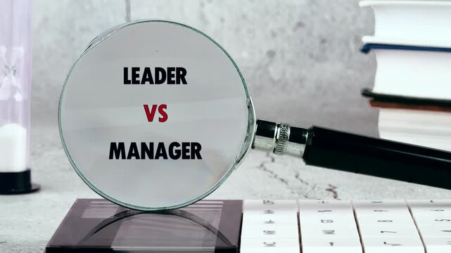 A magnifying glass brings into sharp focus the profound concepts of Leader versus Manager. It rests on a modern office desk with books and an hourglass