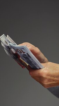 Unrecognizable old mature woman counts cash dollars, holding bundle one hundred dollar banknotes. Arms of senior female holds paper USD money in wrinkled hands after winning lottery bonus. Close up