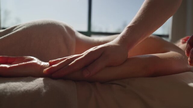 Relaxing full body massage therapy on spa table with soft daylight, soothing touch on arm and back promoting calm relaxation and stress relief for wellness