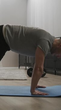 Focused home workout sequence showing a man practicing advanced bodyweight balance exercise on a yoga mat, building strength, stability, and core control indoors
