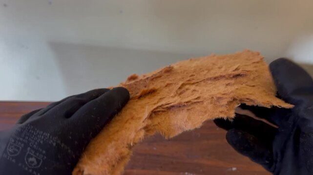 Damaged MDF panel is removed and torn apart to reveal fragile moisture-weakened fibers in close detail.