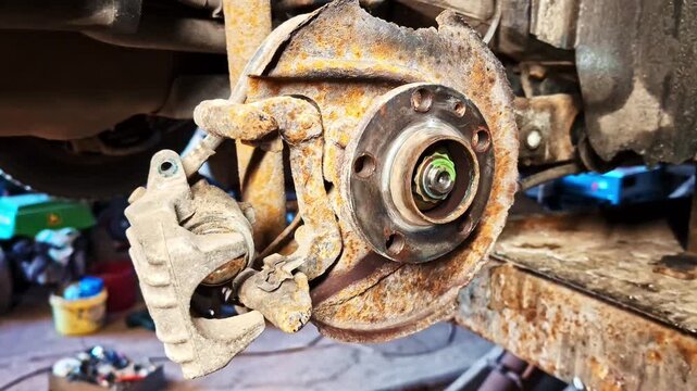 Rusted car brake disc and caliper showing corrosion and needed replacement