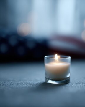 Burning candle placed in front of softly blurred flag background, remembrance concept, respectful atmosphere
