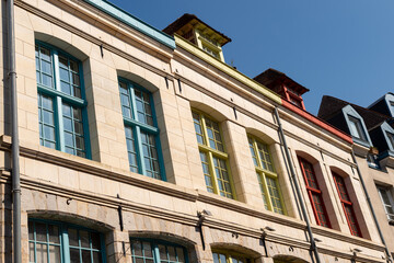 Obraz premium Low angle view of historic stone building facades with colorful blue, yellow, and red window frames in Lille, France.