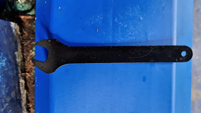 Black Steel Open End Wrench on Blue Background Industrial Hand Tool