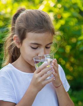 The child drinks water from a glass. Selective focus.