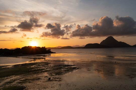 Aerial view of the sun melting into the horizon, painting the clouds with fire as the water reflects the sky's golden hues, Concepcion, Western Visayas, Philippines.