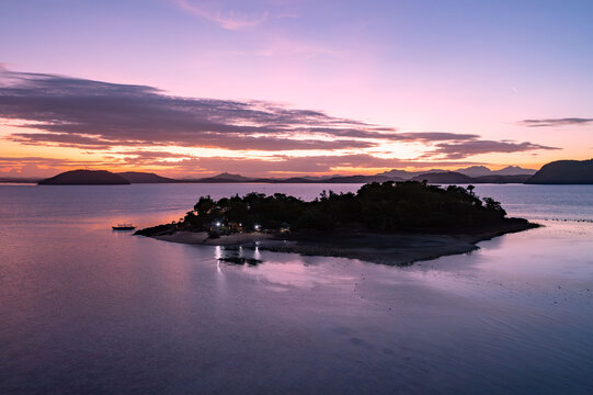 Aerial view of a small island basking in the tranquil embrace of dusk, where the sky's vibrant hues reflect on the calm water, Concepcion, Western Visayas, Philippines.
