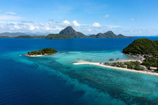 Aerial view of the turquoise waters surrounding lush islands, contrasting with the deep blue sea, a tropical paradise unfolds., Concepcion, Western Visayas, Philippines.