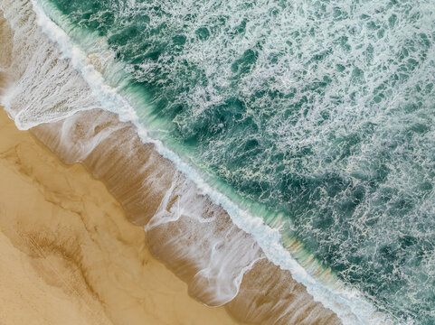 Aerial view of the shoreline where golden sands meet the frothy turquoise waves, creating a mesmerizing dance of color and texture, Quiaios Beach, Figueira da Foz, Portugal.