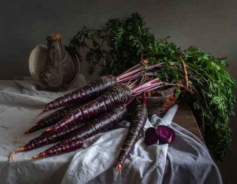 A still life of purple carrots on a table