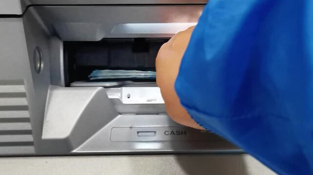 Person withdrawing 50000 denomination banknotes from ATM machine