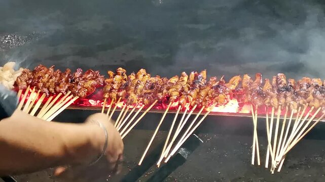Traditional skewered meat satay grilling over hot charcoal flames