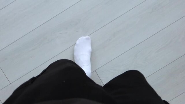 First-person view of footsteps in white socks.
A person walks in socks on a parquet floor.