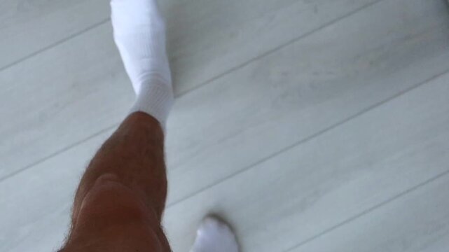 First-person view of footsteps in white socks.
A person walks in socks on a parquet floor.